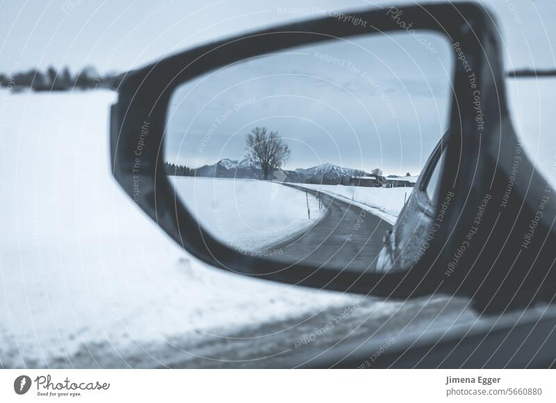 Blick durch den Seitenspiegel im Auto auf eine verschneite und Glatte Straße und Umgebung Rückspiegel Schlechtwetter Schnee Glätte Verkehr glatt Straßenverkehr