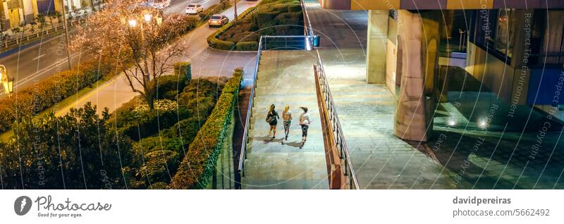 Freundinnen trainieren zusammen in der Stadt bei Nacht unkenntlich Menschengruppe Frauen rennen Abend Großstadt Team Zusammensein Training Straße Verkehr PKW