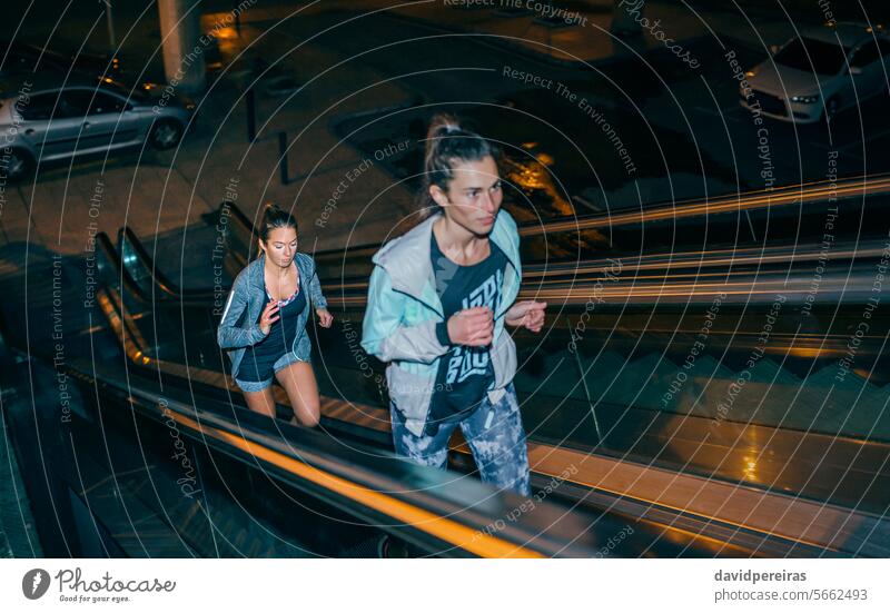 Frauen Freunde Ausbildung laufen auf Rolltreppe in der Stadt in der Nacht rennen Training Läufer Mechaniker Treppe Treppenhaus Schritt nach oben Großstadt Licht