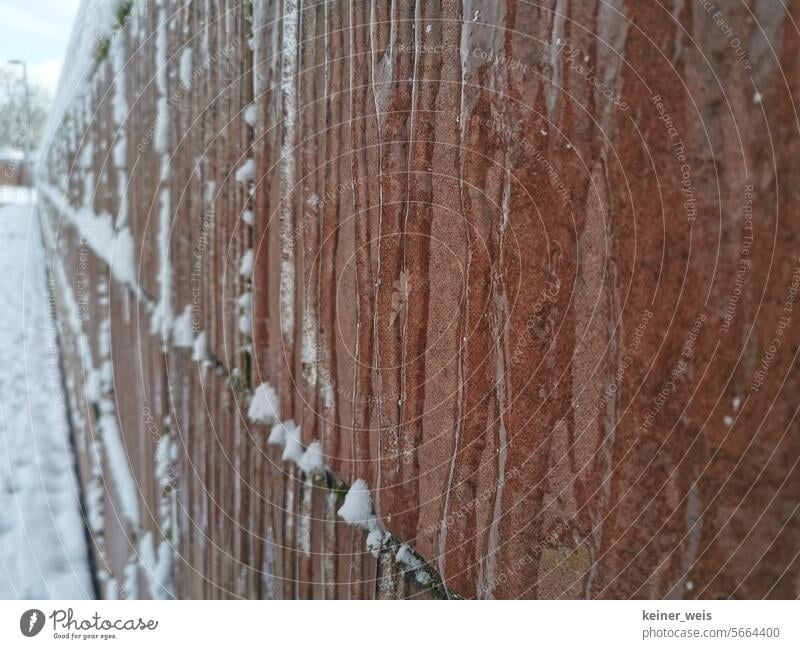 Zu Eis gefrorenes Wasser auf einer Sandsteinmauer mit Schnee Stein eisig Frost Gebäude Gebäudeschaden Frostschutz Frostschäden Schutzmauer frieren kalt Winter