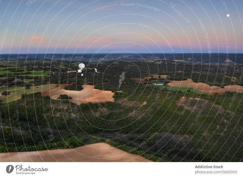 Die Dämmerung senkt sich über Alcarria mit Satellitenschüsseln inmitten der sanften Hügel und dem mondbeschienenen Himmel Antenne Guadalajara Mond Landschaft