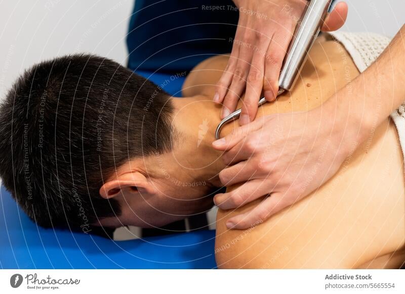 Physiotherapeutische Behandlung mit einem Stahlmassagegerät Physiotherapie Therapeut geduldig männlich Gesundheit medizinisch Rücken Stahlwerkzeug
