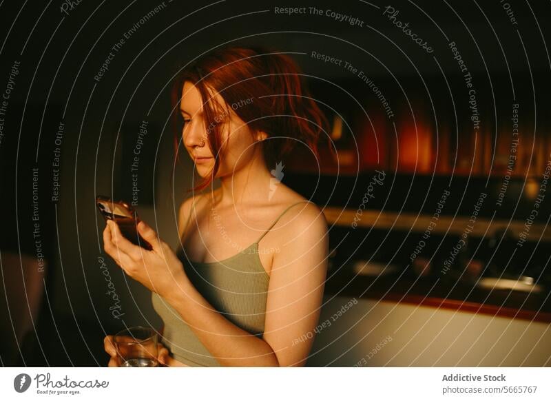 Gelassene Frau mit Smartphone in schwach beleuchtetem Raum Gelassenheit ruhig halbdunkel Beleuchtung warm Ton im Innenbereich Komfort Mitteilung