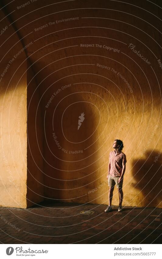 Mann steht allein in einer sonnenbeschienenen Ecke mit tiefen Schatten in Cartagena, Kolumbien Stehen Sonnenlicht Wand warmer Ton beschaulich jung Kontrast