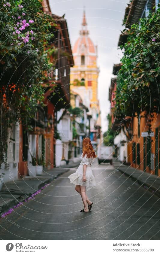 Frau geht auf einer Kopfsteinpflasterstraße in Cartagena, Kolumbien laufen Straße historisch Stadt Architektur kolonial Blumen malerisch rote Haare Kleid Mode