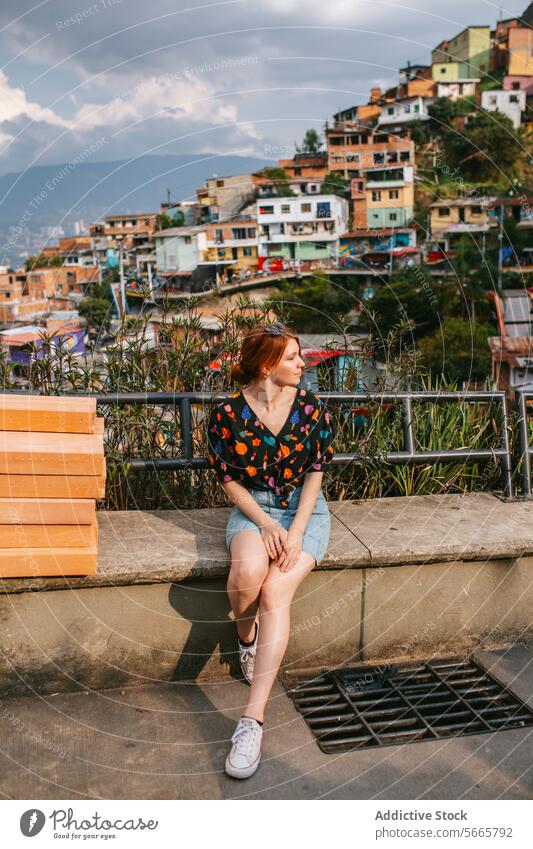 Junge Frau genießt den Anblick der bunten Häuser in Medellin Bank malerisch Ansicht farbenfroh Landschaft hügelig pulsierend wolkig Himmel besinnlich jung