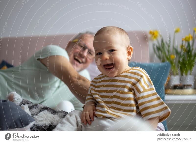 Freudiger Familienmoment mit Baby und Großvater Lächeln heimwärts gemütlich Freude Glück gestreiftes Hemd spielerisch Säugling Holunderbusch Mann Zusammensein