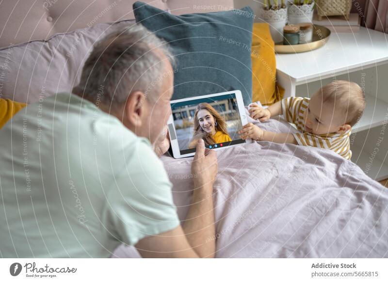 Großvater und Baby führen Videogespräche mit der Familie auf dem Tablet Videoanruf Tablette Bett Kissen Komfort digital Technik & Technologie Säugling Senior