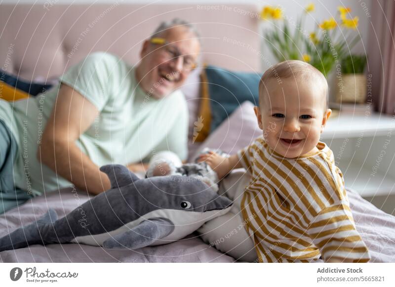 Großvater und Baby, die sich mit einem Plüschtier anfreunden Bonden Spielzeug Lächeln gemütlich Bett ausgestopfter Hai freudig Senior Mann Kind spielen Lachen