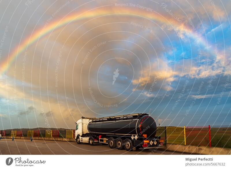 Tankwagen mit Gefahrgut unter einem spektakulären Himmel mit Regenbogen geparkt. Lastwagen Fracht Sonnenuntergang Wetter logistisch Verkehr gefährliche Güter