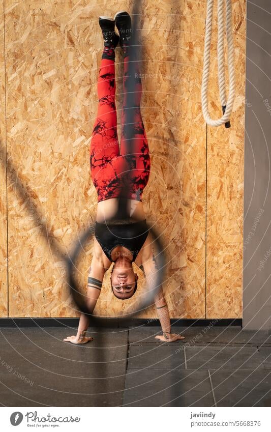 Frau trainiert Gleichgewicht und Kraft in einem Fitnessstudio Training Ausgeglichenheit Stärke Handstand Übung Wand aktiv Kerngehäuse auf den Kopf gestellt