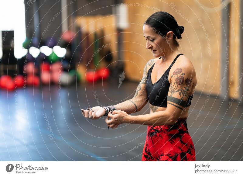 Frau schützt ihr Handgelenk vor dem Training in einem Fitnessstudio horizontal Textfreiraum reif Schutz Übung Vorbereitung Wellness Gesundheit Ermächtigung