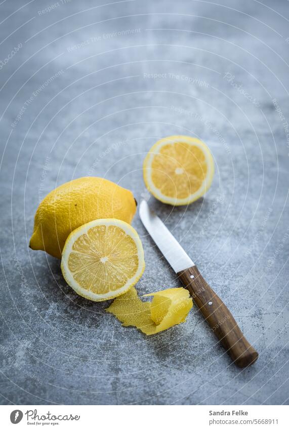 Zitronen mit Messer auf grauem Hintergrund frisch Lebensmittel Zitrusfrüchte natürlich Gesundheit gelb Frucht Ernährung Diät Vegetarische Ernährung saftig