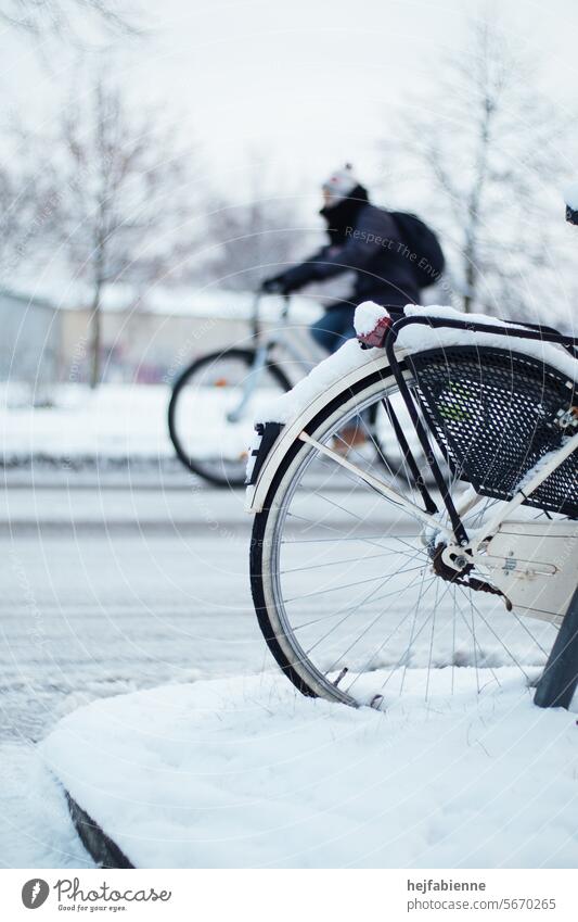 Fahrradfahren im Winter auf schneebedeckten Straßen und Fahrradfahrer im Hintergrund Schnee Frost Straßenverkehr Fahrradfarer Tiefenunschärfe Hinterrad