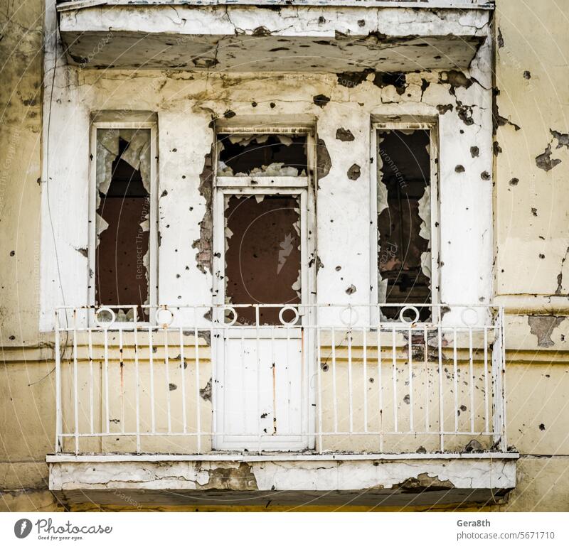Zerstörtes Haus mit Geschossspuren in den Wänden während des Krieges in der Ukraine Verlassen Architektur Balkon Baustein gebrochen Gebäude Einschusslöcher