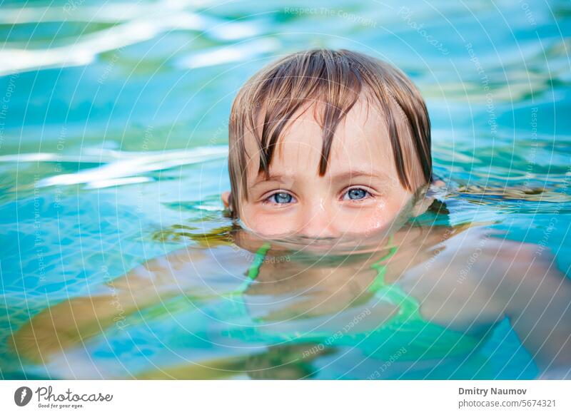 Kind schwimmt in einem Pool in die Kamera schauen Aktivität Hinterhof blau Kaukasier Kindheit niedlich Spaß Garten Mädchen Kopf Freizeit Lifestyle wenig