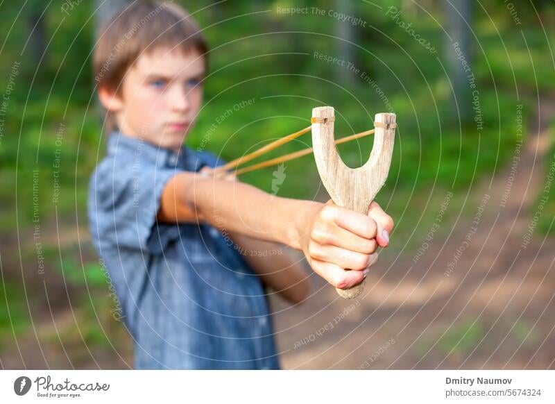 Kind mit Steinschleuder Genauigkeit Aktivität zielen Arme schlecht Bohnenschütze Verhalten Junge Gören Kaukasier Gefahr Gesicht Flip Spaß Spiel Hand