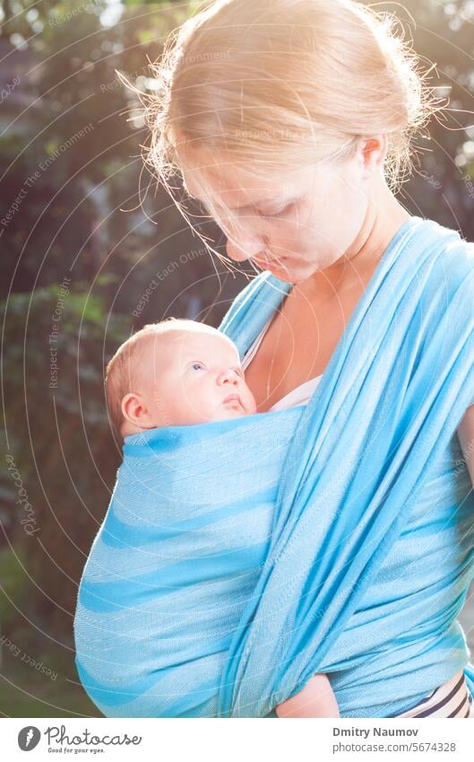 Junge Mutter trägt ihr kleines Mädchen im blauen Tragetuch 0-6 Monate Erwachsener anhänglich Baby schön Decke Bonden hell Bündel Pflege führen Kaukasier Kind