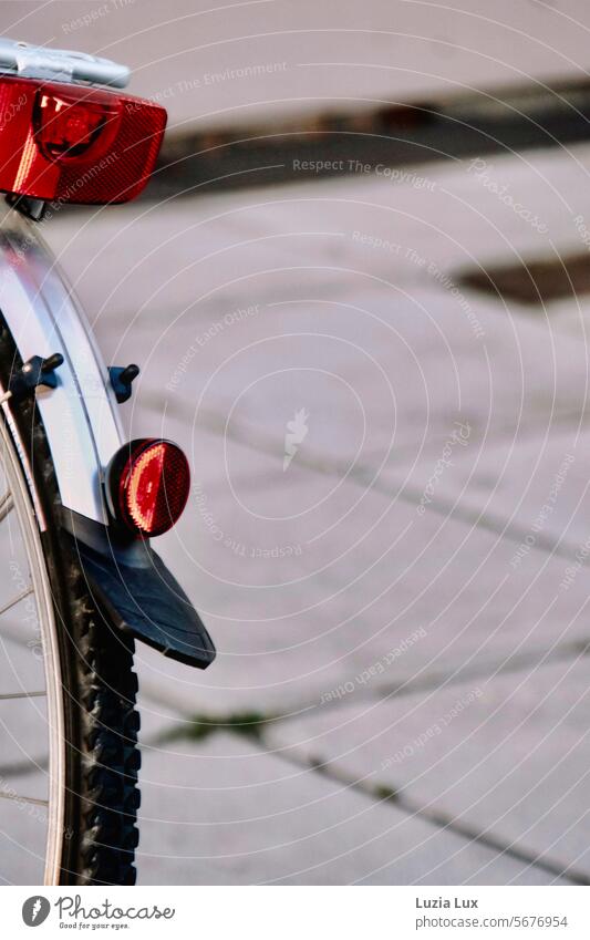 rotes Fahrradrücklicht Fahrrrad Rücklicht Licht Verkehr Reflektor Katzenauge Schutzblech Reifen Rad Speichen Fahrradfahren Detailaufnahme parken