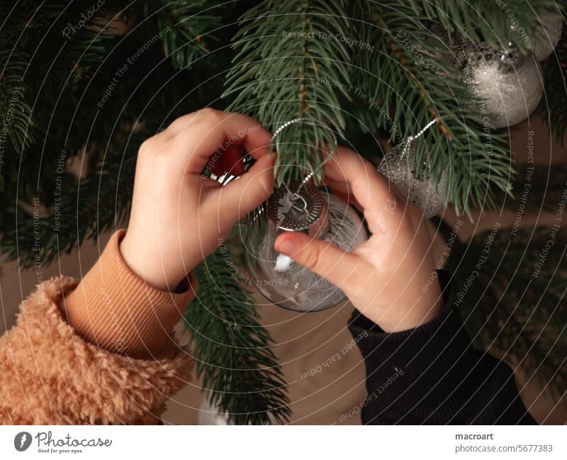 Kind hängt Christbaumkugel an den Weihnachtsbaum Baum christbaum baumschmuck weihnachtsschmuck weihnachtsbaum christbaumkugel glaskugel weihnachtlich hände