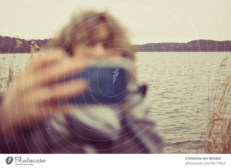 verschwommenes Portrait einer Frau, die mit dem Smartphone fotografiert fotografieren Handy Mensch Mobile Smartphonefotografie unscharf Telefon Seeufer Natur