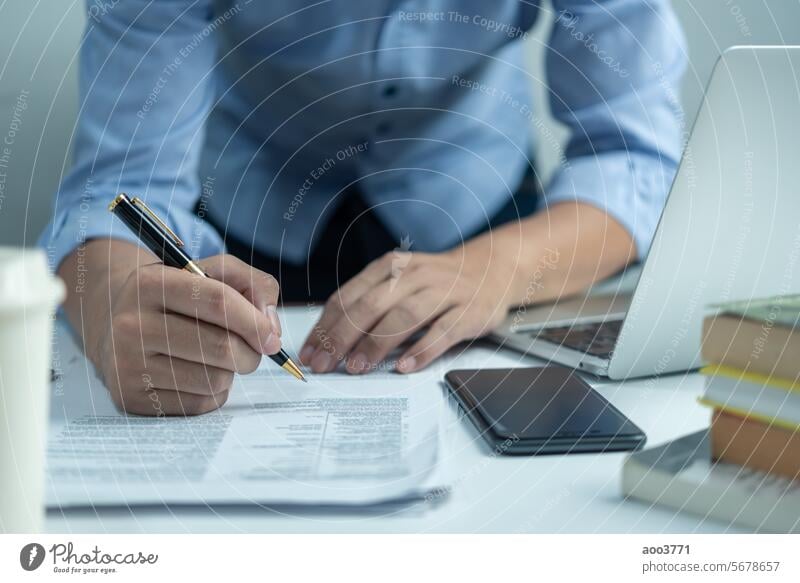 Männliche Hand, die einen Stift hält, um ein Dokument zu schreiben oder einen Geschäfts- oder Rechtsvertrag zu unterzeichnen. Checkliste von Finanzdokumenten und Marktberichten