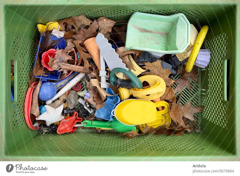 Blick in eine grüne Kunststoffkiste mit Sandkastenspielzeug und Herbstlaub Sandkiste Spielzeug Spielen Kindheit Kinderspiel Kindergarten Spielplatz Kistr Kasten