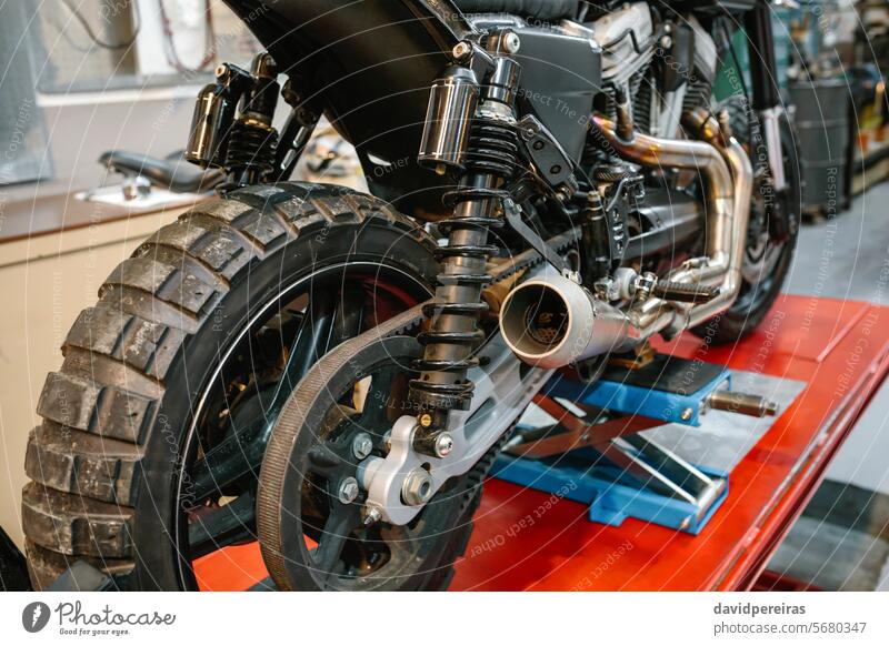 Rückansicht des Auspuffs und des Stoßdämpfers eines Custom-Motorrads in der Fabrik benutzerdefiniert Röhren Schock Absorber Werkstatt Garage Podest Rücken