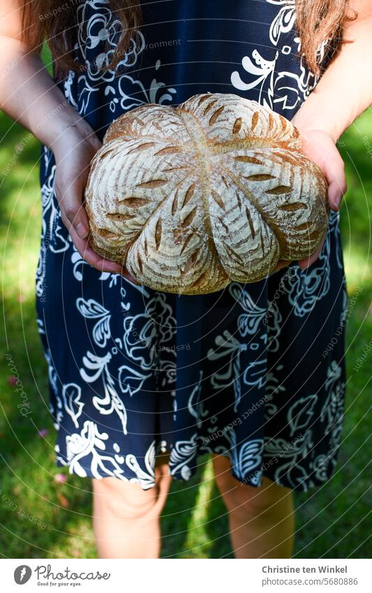 ein schön verziertes Brot in den Händen einer jungen Frau Brotlaib festhalten selbstgemacht Lebensmittel frisch geschmackvoll Kruste Ernährung gebacken lecker