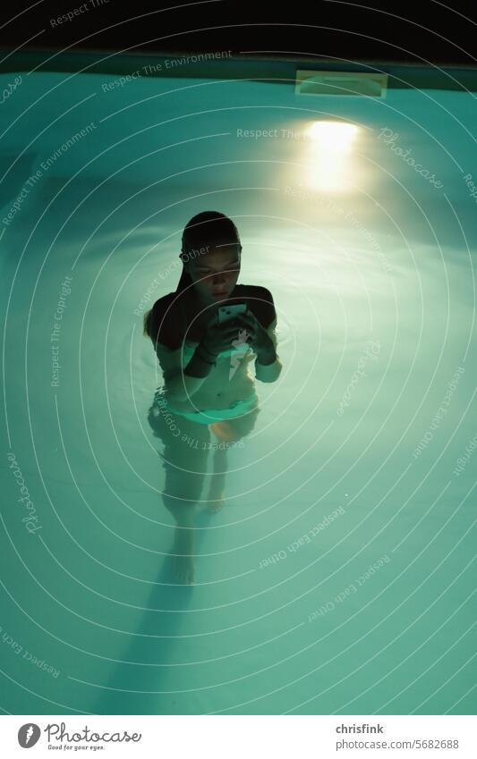 Mädchen steht im Swimmingpool und schaut auf Handy Frau Kind Pool digital ablenkung nacht dunkel Wasser Sommer Schwimmen & Baden Erholung Erfrischung