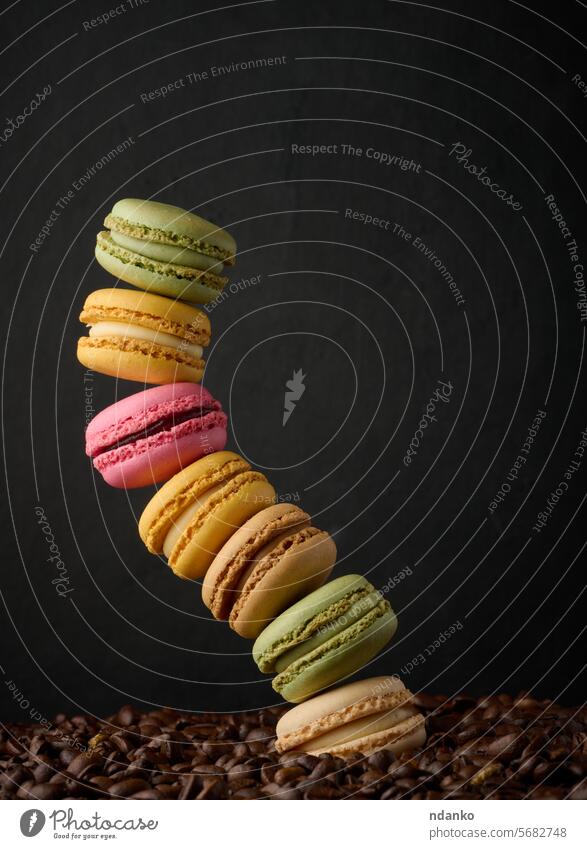 Stapel von mehrfarbigen Macarons auf einem Hintergrund von Kaffeebohnen, schwarzer Hintergrund Bohne Französisch Makrone Schaumgebäck süß Mandel Bäckerei