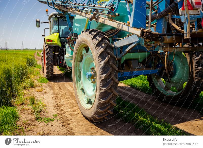 Tiefansicht eines Traktors mit angebauter Spritze bei der Fahrt auf einer verschmutzten Straße Aerosol landwirtschaftlich Ackerbau biochemisch Pflege Müsli