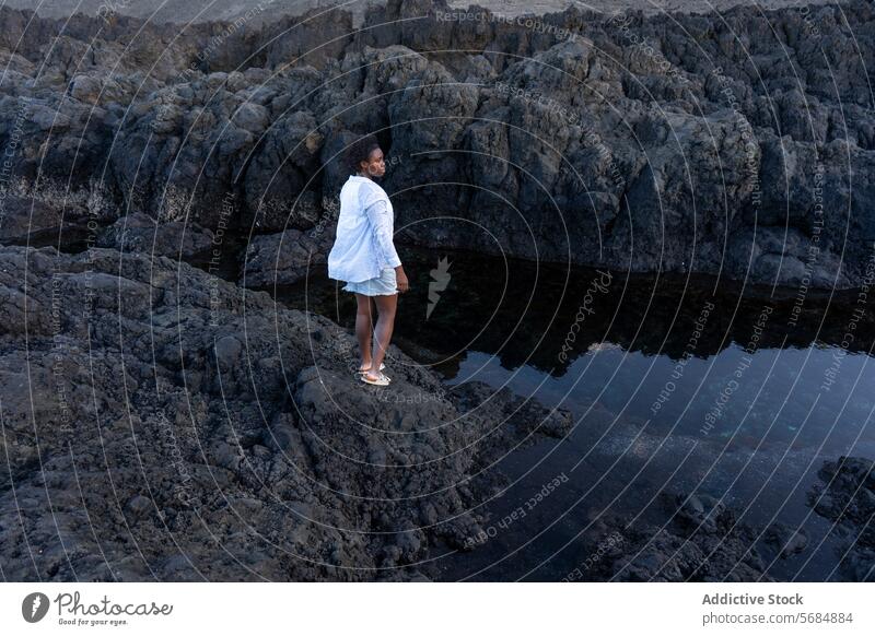 Schwarze Frau, die auf einer felsigen Klippe steht Reisender See Landschaft Berge u. Gebirge Wasser Reflexion & Spiegelung Natur jung Afroamerikaner ethnisch