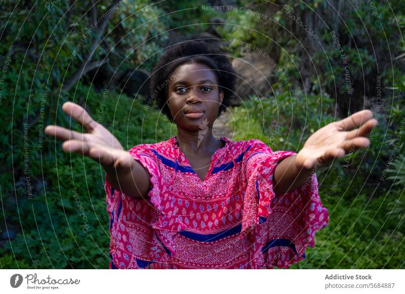 Glückliche schwarze junge Frau, die mit offenen Händen einlädt einladen Handfläche Wald Baum positiv Umwelt Natur Afroamerikaner ethnisch Willkommen Park stehen