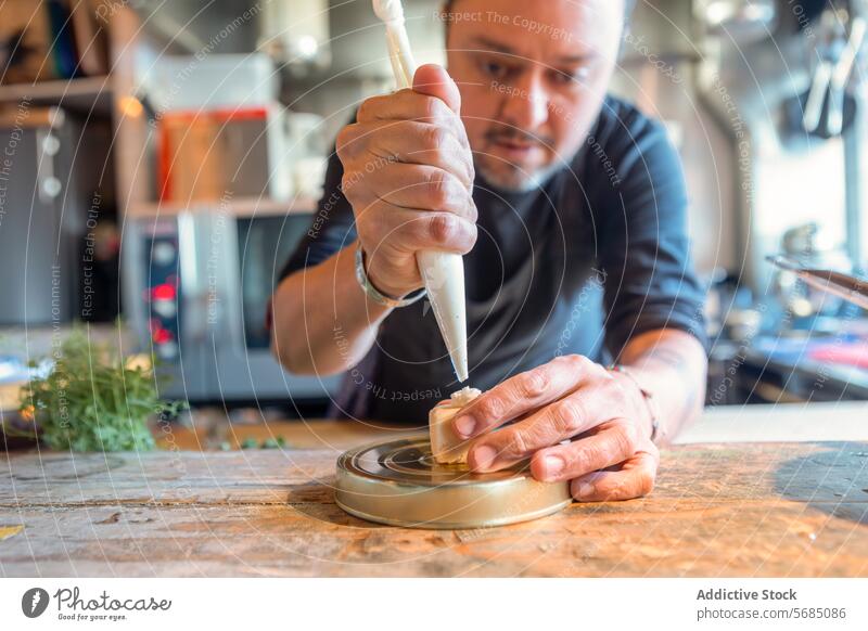 Konzentrierter Mann legt Sahne auf Käsedessert Küchenchef Dessert Fokus Restaurant geschmackvoll Konzentration Backwarenbeutel italienische Küche Küchengeräte