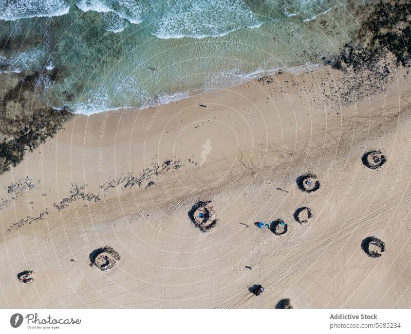 Overhead-Aufnahme der einzigartigen spiralförmigen Felsformationen in den Dünen von Corralejo mit an Land gespülten Wellen auf Fuerteventura Antenne Ansicht