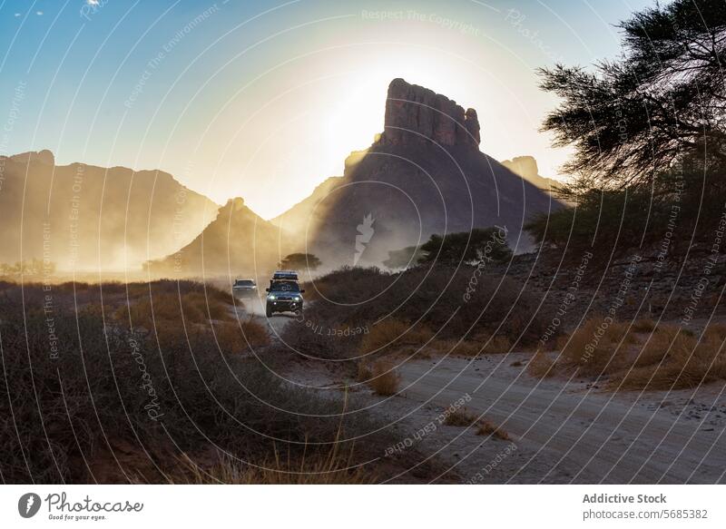 Fahrt bei Sonnenuntergang durch die staubige Landschaft von Guelta Essendilene Off-Road Fahrzeuge Gelände guelta essendilene Gesteinsformationen Abenteuer