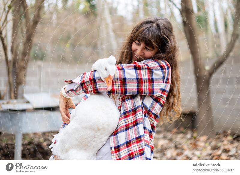 Bäuerin umarmt eine Gans auf einem Bauernhof im Freien Erwachsener Ackerbau Tier Hinterhof Schnabel Vogel Zucht Pflege Kaukasier Müsli Landschaft heimisch Ente