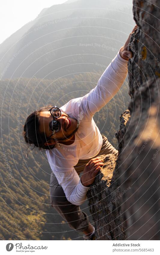 Mutiger junger Mann klettert auf einen Bergfelsen Aufstieg Berge u. Gebirge Kamm positiv Sonnenbrille Stil Klippe Stoff Natur Abenteuer Hochland reisen männlich