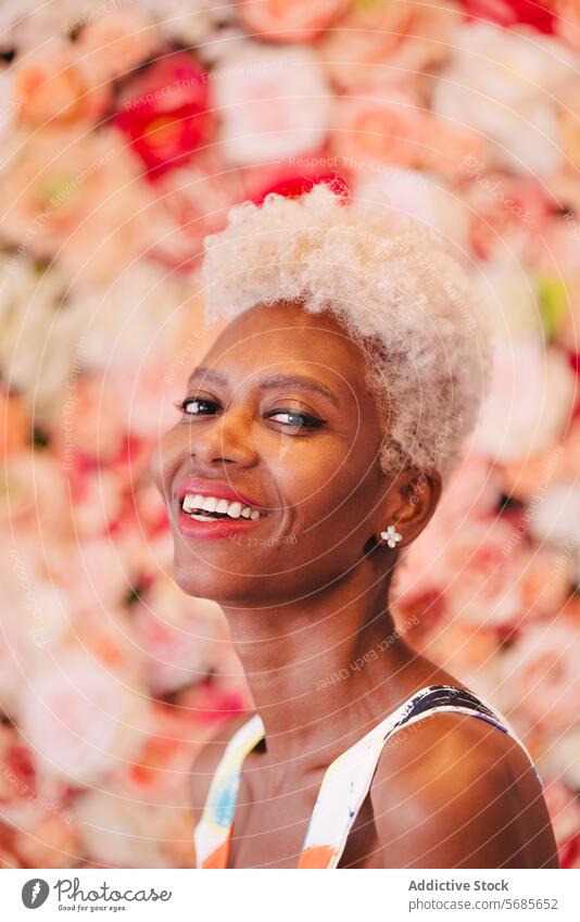 Lächelnde schwarze Frau in der Nähe von rosa blühenden Blumen Sommer Blumenstrauß Glück Blütezeit heiter geblümt positiv charmant genießen Stil farbenfroh