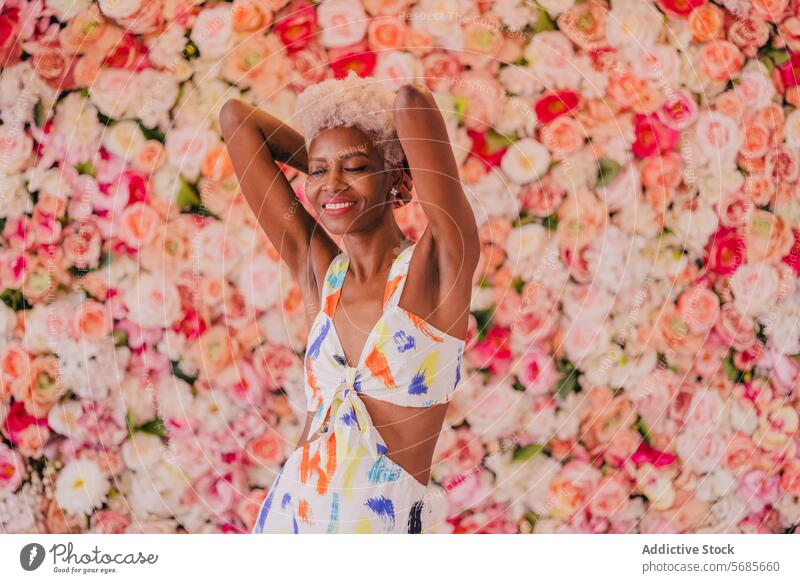 Elegante schwarze Frau in stilvollem Sommerkleid mit erhobenen Armen Blume geblümt Stil sinnlich Blütezeit elegant Blumenstrauß jung Glück Lächeln feminin