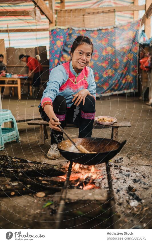 Asiatische Frau bei der Zubereitung von Speisen in einer Küche mit Bratpfanne vorbereiten Lebensmittel Wok Dame sitzen Koch Zange Bank schäbig braten Utensil