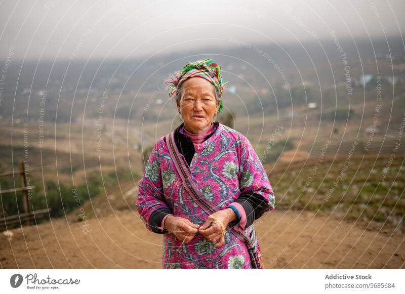 Ethnische Frau mittleren Alters steht auf einem Feld selbstbewusst Landwirt ländlich Zaun Weg Landschaft Ackerbau Natur reif Bauernhof Dorf Schonung Haus
