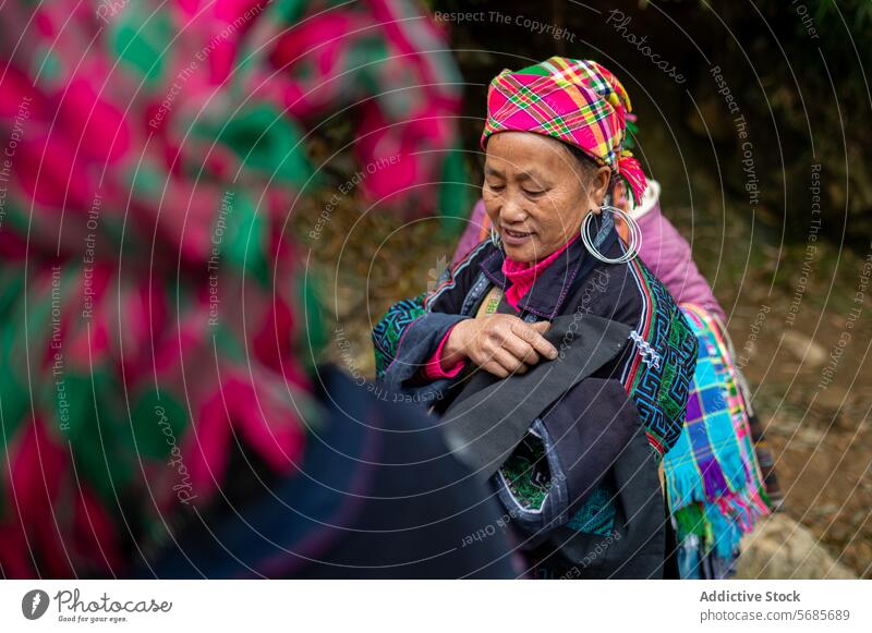 Lächelnde ältere Frau mit Kleidung in den Händen, die draußen steht Dorf Weg Tradition Kultur Landschaft Kopftuch Senior Wohnsiedlung lokal gealtert positiv