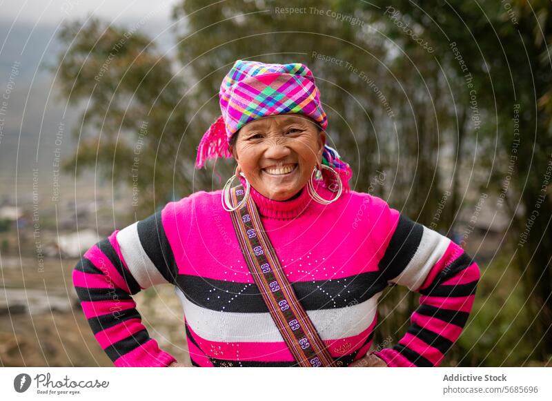 Ältere Frau in warmer Kleidung auf einem Hügel stehend warme Kleidung heiter Pullover Lächeln Berghang älter Senior Natur Glück Baum positiv Sonne ländlich