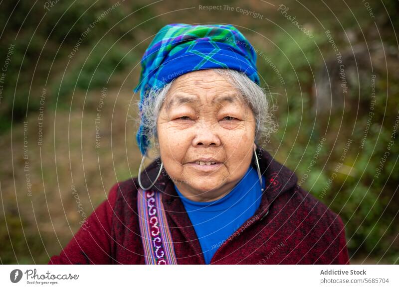 Positive ältere Frau, die in die Kamera schaut, mit unscharfem Hintergrund in Vietnam stehen warme Kleidung Schal heiter positiv Lächeln Landschaft Senior