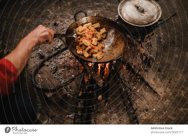 Gesichtslose Person, die Essen in der Pfanne brät in der Pfanne braten Feuer Hand Spachtel drehen. Bratpfanne Feiertag Ausflug Koch Flamme Küche vorbereiten