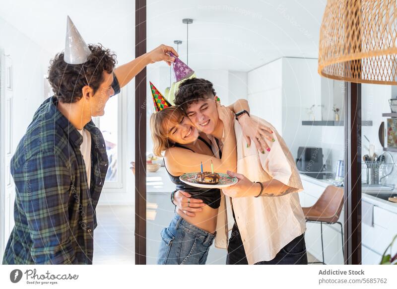 Glückliche Freunde haben Spaß Moment zusammen in der modernen Küche Männer Frau feiern Geburtstag Freude Umarmung Glockenhut Kuchen Spaß haben Lächeln Party