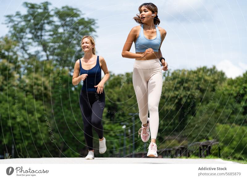 Fröhliche Sportlerinnen joggen auf der Straße Frauen Training Herz Sportkleidung Turnschuh positiv heiter Fitness Gesundheit Athlet Zusammensein Sportbekleidung
