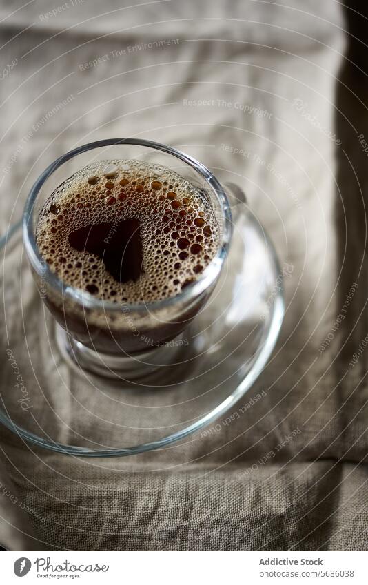 Nahaufnahme von frischem Kaffee in einer klaren Glastasse Tasse Getränk trinken schaumig gebraut Textur Gewebe Hintergrund übersichtlich durchsichtig